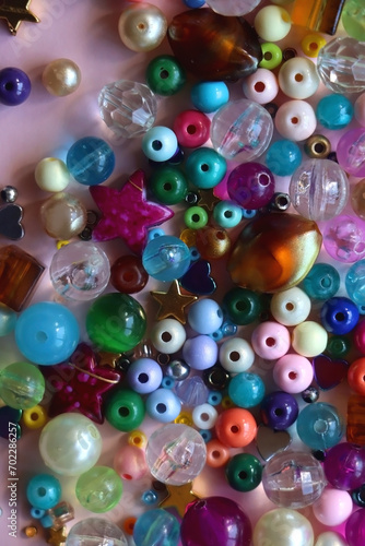 Various colorful beads on bright pink background. Top view.