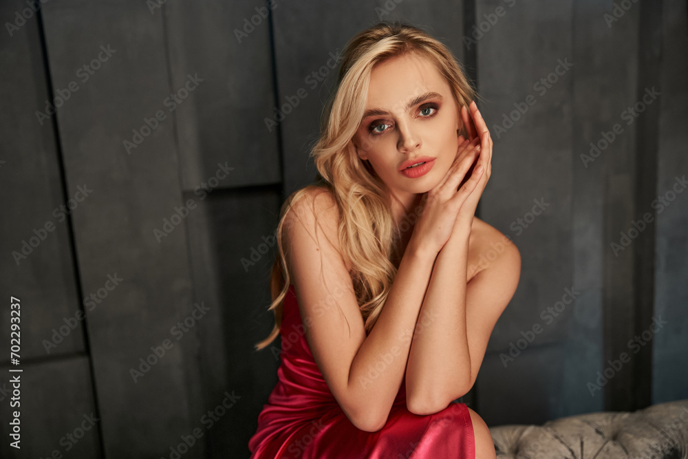 appealing sensual blonde woman in elegant evening dress posing and looking straight at camera