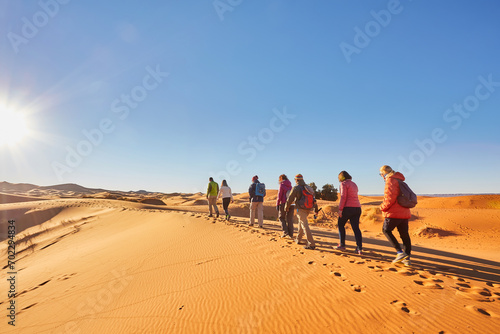 A group of tourists explores the majestic sand dunes of the Sahara Desert