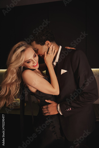 handsome jolly african american man in elegant clothes hugging his happy beautiful girlfriend