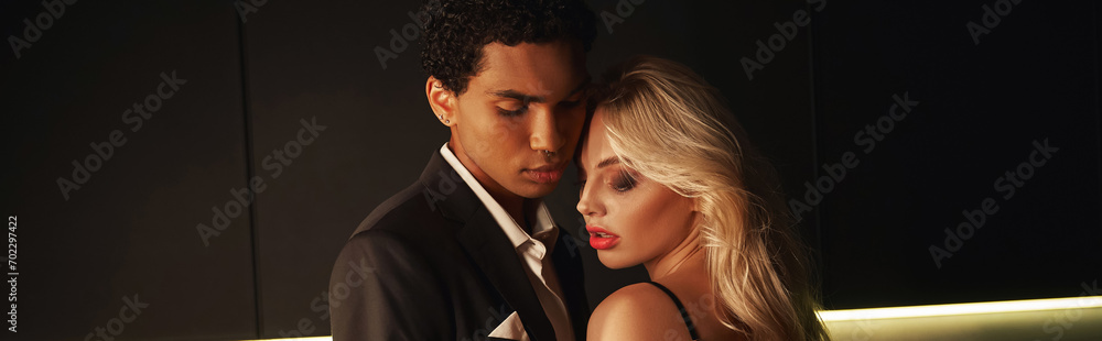 young loving interracial couple in evening attires posing lovingly together at home, banner