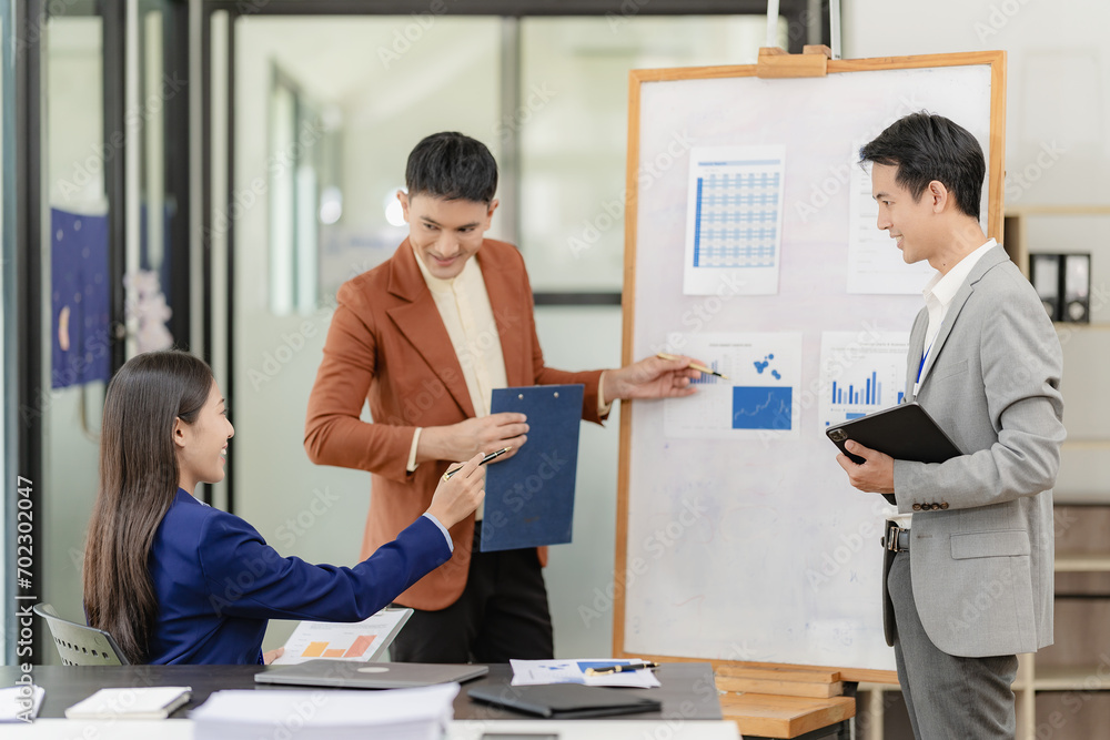 Obraz premium Team of successful Asian businessmen in suits working in conference room to discuss brainstorming, computation, analysis together on company growth goals and gross profit margins.