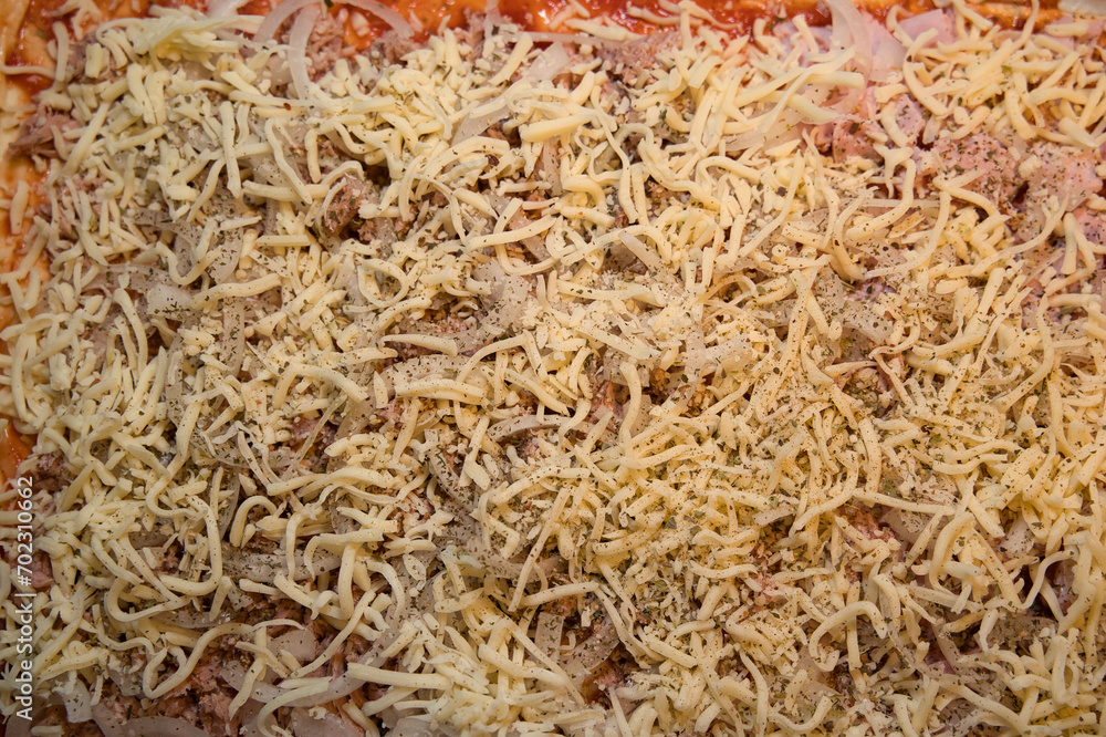 Tuna and ham sprinkled with cheese on oven-ready pizza dough Tuna and ham sprinkled with cheese on oven-ready pizza dough