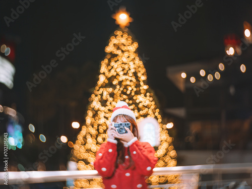 Young woman holding camera in red dress with Christmas lights