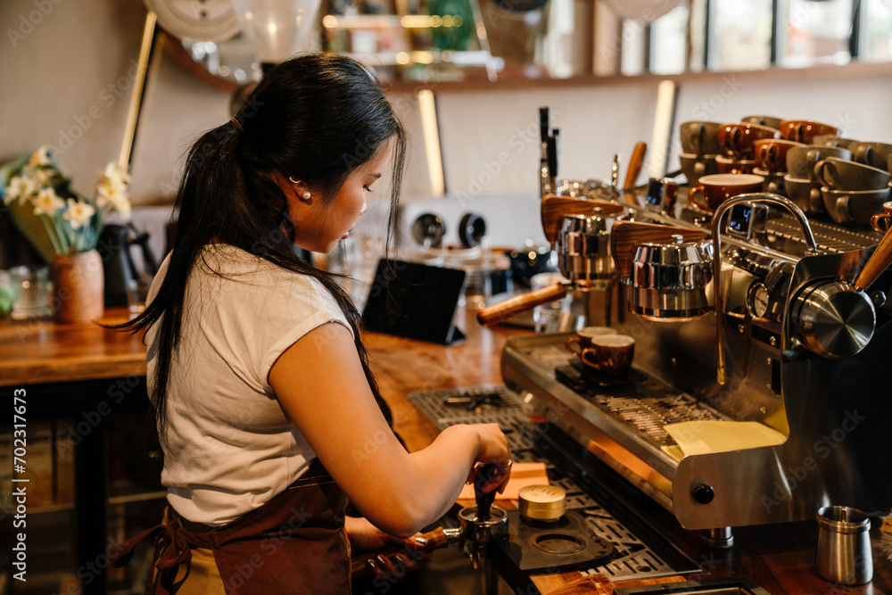 Young woman barista making cup of coffee using espresso machine Young woman barista making cup of coffee using espresso machine