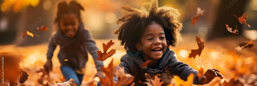 black kids playing in autumn leaves on a sunny day - obrazy, fototapety, plakaty 