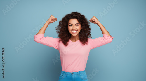 strong woman dressed in pink smiling on a light blue background showing her muscles  photo