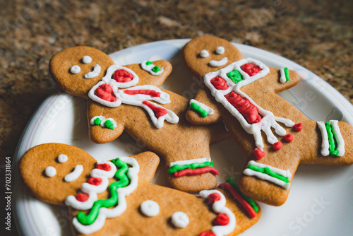 Three colorful gingerbread men cookies with green and red frosting on a white plate