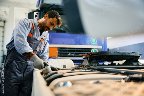 Truck mechanic inspecting vehicle in garage. photo