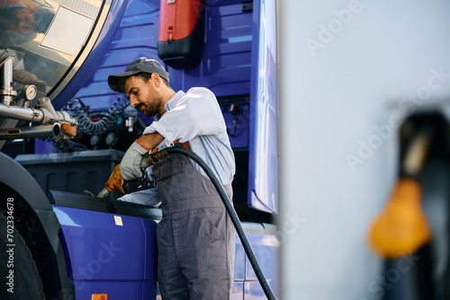 Maintenance worker filling truck fuel tank.