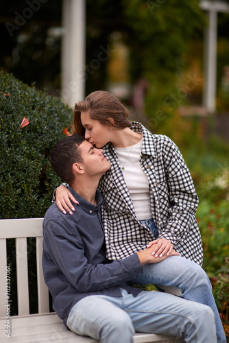 Autumn Romance: Young Couple Embracing and Kissing on Park Bench. Young couple kissing and rejoices at the lake. lovely young couple kissing outdoors in autumn. Embraced in Autumn's Warmth: Couple's © andreiko