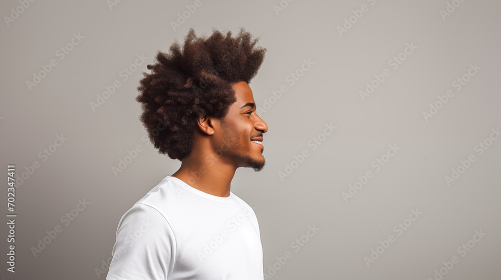 Obraz premium Modern young man showcasing his curly Afro hair against a neutral background.