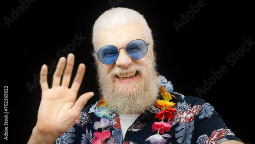 Senior man in a Hawaiian shirt and sunglasses talks with his family while on holiday, sharing joyous moments