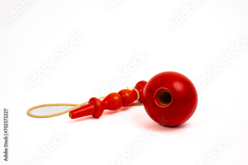 A studio shot of a bright red French "Bilboquet" or cup and ball game made out of wood