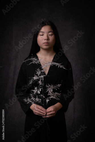 classic renaissance portrait of an asian woman in black dress  holding silver brances photo