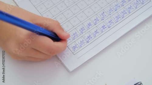 Close-up of hand of child writing Chinese characters in the notebook. Language learning and homeschooling concept photo