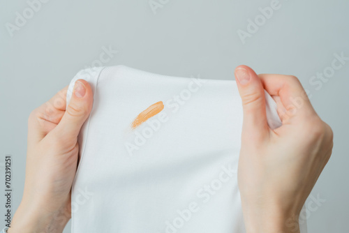 Cosmetic stains on the white clothes. The housewife evaluates the stain before removal. Liquid foundation cream. daily life stain and cleaning concept. 