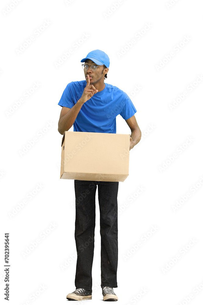 A male deliveryman, on a white background, in full height, with a box, shows a sign of silence A male deliveryman, on a white background, in full height, with a box, shows a sign of silence