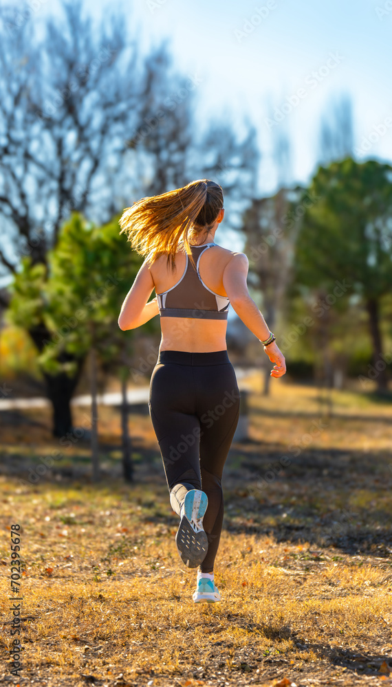 Beautiful young runner, dressed in tight sportswear and top, running with her ponytail blowing in the wind illuminated by dawn sunlight in a mountain park. Beautiful young runner, dressed in tight sportswear and top, running with her ponytail blowing in the wind illuminated by dawn sunlight in a mountain park.