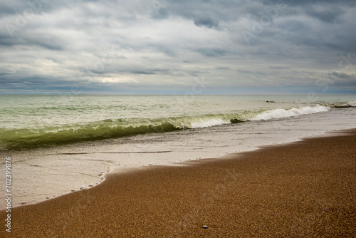 Photography waves breaking on a sandy  beach with dramatic clouds shot at kew beach toronto