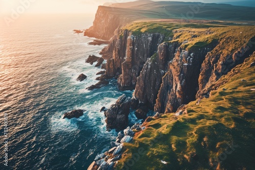 Photo A rugged promontory rises above the sparkling sea, its grassy cliffs meeting the