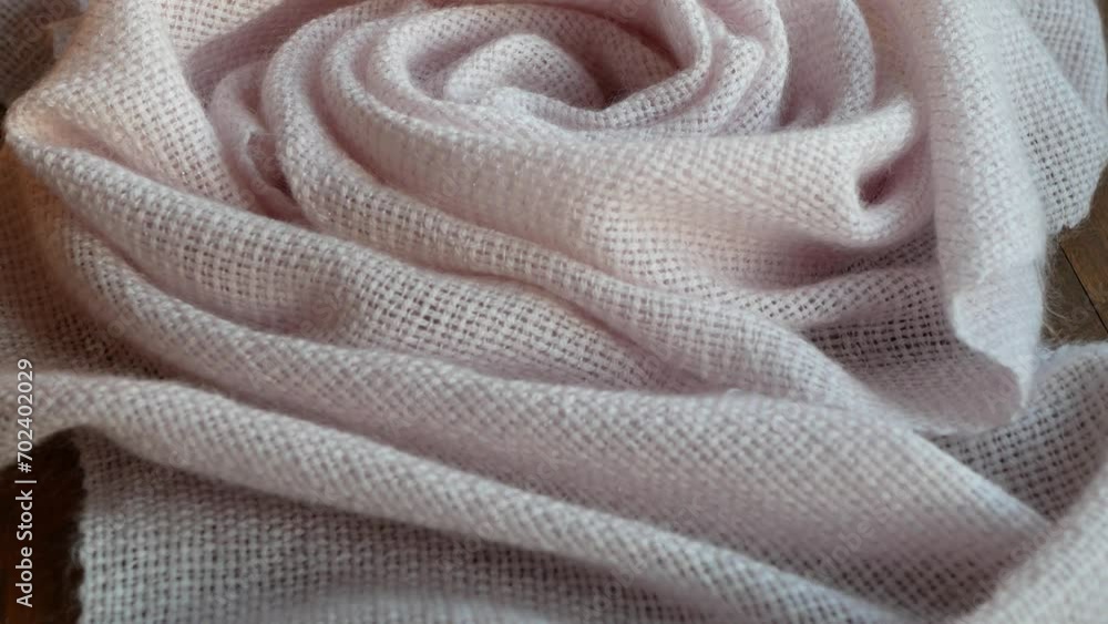 Draped soft woolen light pink fabric of shawl or blanket, close up. Beautiful and delicate handmade accessory or garment, selective focus Draped soft woolen light pink fabric of shawl or blanket, close up. Beautiful and delicate handmade accessory or garment, selective focus