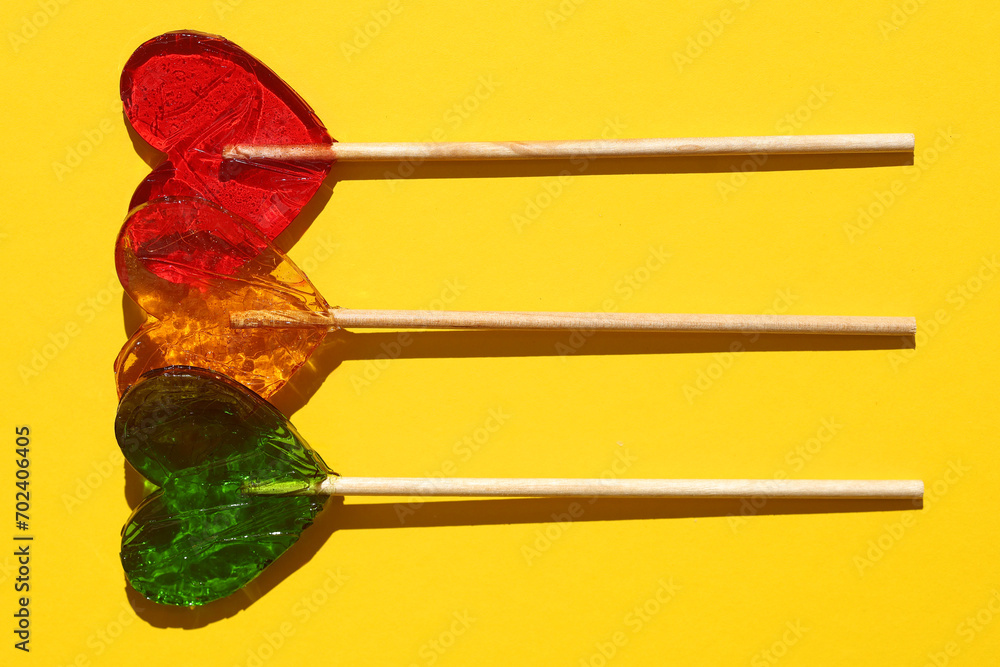 Sweets concept, lollipop heart on sticks on yellow background Sweets concept, lollipop heart on sticks on yellow background