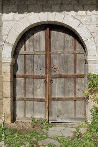 Old colorless, double leaf, round arch wood door on stone wall, Rruga Kristaq Tutulani Street, Gorica district. Berat-Albania-070 photo