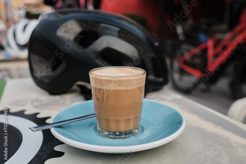 Coffee cycling ride. Cyclist enjoying coffee in the cafe after riding. Cup coffee and cycling helmet on table.