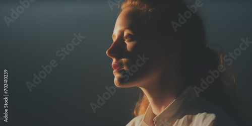 Intense profile of a woman with her face half-illuminated by golden light photo