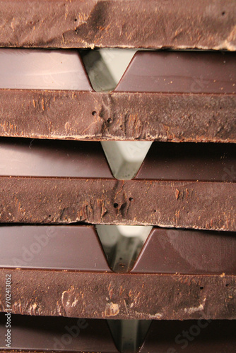 A stack of extra dark bitter chocolate bar pieces stacked in horizontal rows close up. Vertical photo. photo