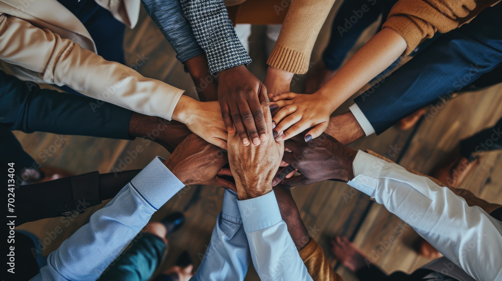 A top-down view of a group of friends stacking their hands together, symbolizing unity, teamwork, and mutual support in a casual setting. A top-down view of a group of friends stacking their hands together, symbolizing unity, teamwork, and mutual support in a casual setting.