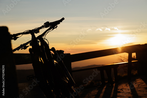 Viaggiare in bicicletta. Fare un viaggio o sport con la bicicletta. vista dettagliata di due biciclette, appoggiate ad uno steccato, in controluce, al tramonto photo