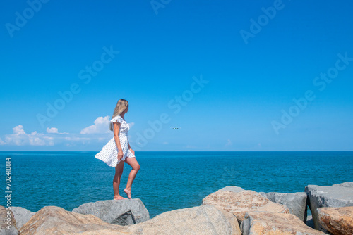 Seaside Chic: A Girl in a White Dress by the Serene Blue Sea