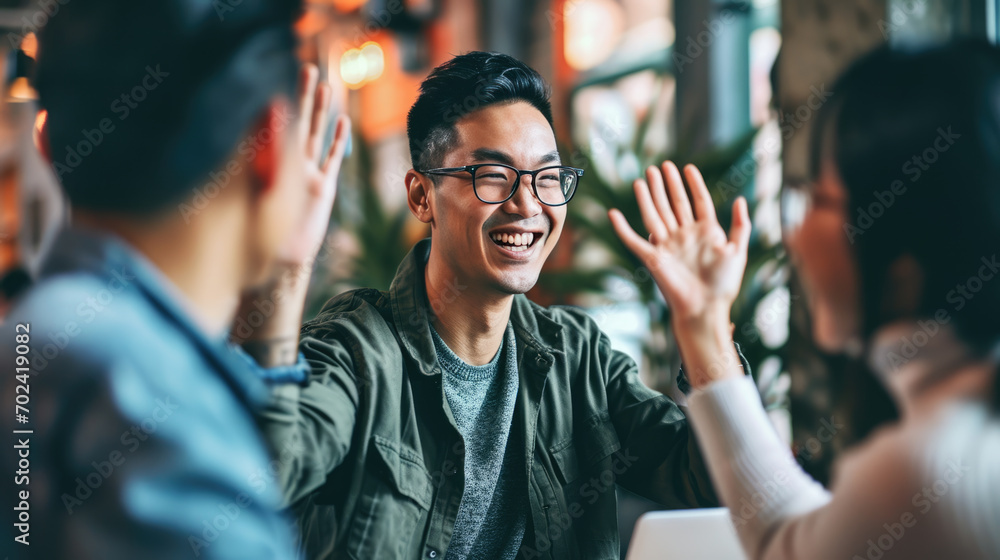Fototapeta premium Businessman smiling and giving a high-five to a person whose back is facing the camera