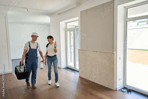 Smiling woman showing new modern comfortable townhouse for focused repairman