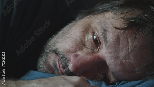 Insomnia concept, closeup of middle aged adult man lying his head on the pillow while trying to fall asleep at night, overthinking and anxiety concept photo