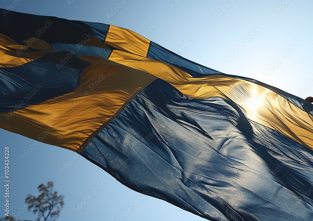 A photorealistic image of the Swedish flag waving gracefully against a clear blue sky, captured from