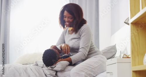 Hug, tickle and mother with boy child on a bed happy, playful and having fun in their home together. Black family, love and mom with kid in bedroom embrace, smile and bonding on vacation in a house photo