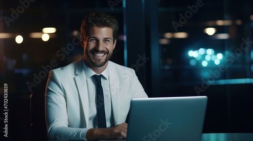 Late at Night in Private Office white male Businessman Works on a Laptop Computer. He Look at the Camera with Smile. Data Protection Engineering Network for Cyber Security, generative ai