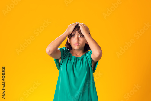 Sad kid girl holding her head over yellow background. Frustration concept © Aleksej