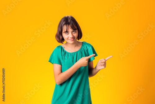 Smiling child pointing hand at space over yellow background