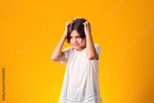 Sad kid girl holding her head over yellow background. Frustration concept