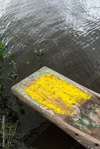 Detail of the bottom of a canoe painted yellow, against the dark river. photo