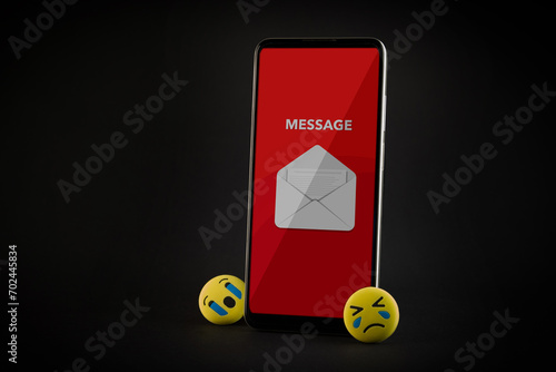 Emoji face and smartphone on black background. Emoticon concept.