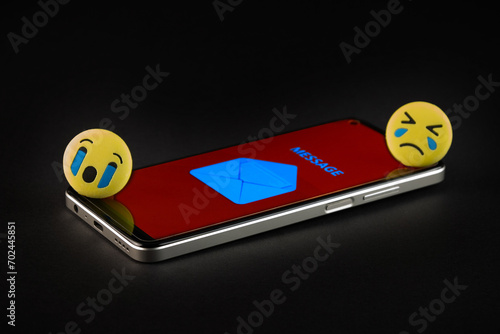 Emoji face and smartphone on black background. Emoticon concept.