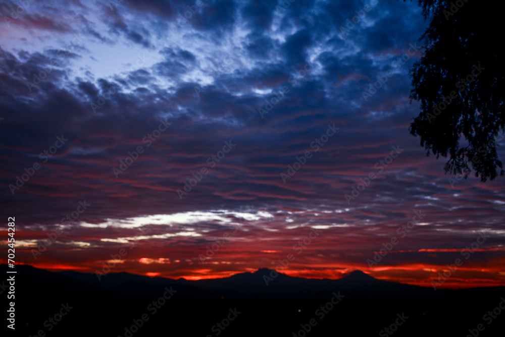 Rojo amanecer, cielo nublado, popocatepetl y 
Iztaccíhuatl
