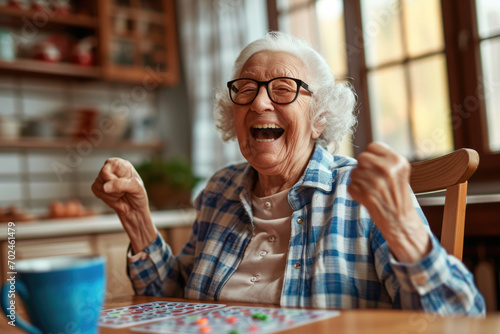 Happy old lady playing bingo at her home kitchen photo