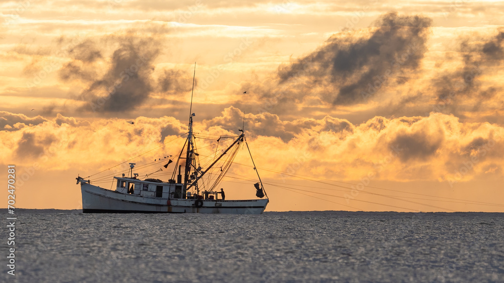 shrimp boat on the water during an orange sunrise