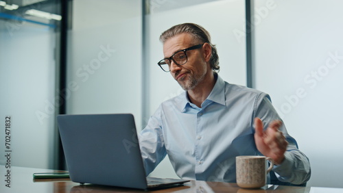 Overworking man drinking coffee in evening office. Businessman typing laptop